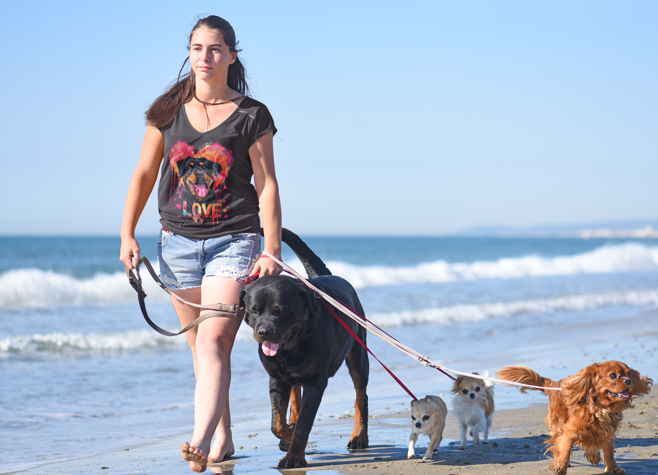 Woman-walking-on-the-beach-with-her-Rottweiler